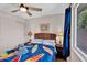 Bedroom features a ceiling fan, wood flooring, and beach themed bedding with view to the backyard at 560 W Duke Dr, Tempe, AZ 85283