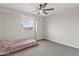 Cozy bedroom features neutral tones, carpet, ceiling fan, and a bright window for natural light at 8912 W Sheridan St, Phoenix, AZ 85037