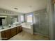 Bright bathroom featuring double sinks, soaking tub, glass-enclosed shower, and window at 11906 N 154Th N Ln, Surprise, AZ 85379