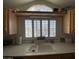 Kitchen sink with white counter, upper shelf, and window with white shutters at 1318 W Chesapeake Dr, Apache Junction, AZ 85119