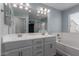 Bright bathroom with double sink vanity, bathtub, and glass-enclosed shower at 14231 W Bronco Trl, Surprise, AZ 85387