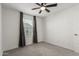 This cozy bedroom features a ceiling fan, neutral carpet and a bright window at 14231 W Bronco Trl, Surprise, AZ 85387