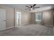 Carpeted bedroom featuring a ceiling fan, a window, and access to the ensuite bathroom at 14231 W Bronco Trl, Surprise, AZ 85387