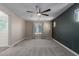 Large carpeted bedroom with ceiling fan, window with blinds, and ensuite bath access at 14231 W Bronco Trl, Surprise, AZ 85387
