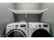 This is a laundry room showcasing a new front load washer and dryer set with shelf at 14231 W Bronco Trl, Surprise, AZ 85387
