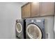 Laundry room featuring side-by-side washer and dryer with wooden cabinets above at 15133 W Moreland St, Goodyear, AZ 85338