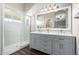 Bathroom features gray cabinets, double sinks, quartz countertops, and a tile shower at 17606 N 2Nd Ave, Phoenix, AZ 85023