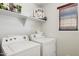 Bright laundry room with modern washer and dryer, open shelving, and natural light from the window with horizontal blinds at 2096 S Moccasin Trl, Gilbert, AZ 85295