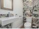 Modern half-bathroom featuring a sleek wall-mounted sink and unique graffiti-style tile accent wall at 225 W Winged Foot Rd, Phoenix, AZ 85023
