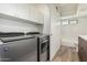 Convenient laundry room with modern washer and dryer units, as well as a stylish barn door entry to the bathroom at 225 W Winged Foot Rd, Phoenix, AZ 85023