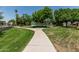 Well-maintained walkway through lush green space under mature shade trees on a clear day at 225 W Winged Foot Rd, Phoenix, AZ 85023