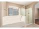 Bathroom features separate tub and enclosed glass shower with large window at 25732 W Elizabeth Ave, Buckeye, AZ 85326