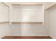 Spacious walk-in closet featuring wood rods, white walls, and hardwood flooring for optimal storage and organization at 25732 W Elizabeth Ave, Buckeye, AZ 85326