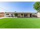 Expansive backyard with lush artificial turf, covered patio, and well-kept exterior, perfect for entertainment at 3010 E Yucca St, Phoenix, AZ 85028