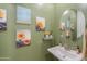 Charming powder room with sunflower decor, a white pedestal sink, and a round mirror at 3855 S Mcqueen Rd # 12, Chandler, AZ 85286