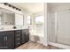 Bathroom featuring double vanity, framed mirror, a separate tub under a window, and walk-in shower at 3875 E Claxton Ave, Gilbert, AZ 85297