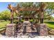 View of clubhouse entrance framed by pergola with stone supports and wooden benches at 3875 E Claxton Ave, Gilbert, AZ 85297