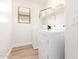 Well-lit laundry room featuring a white washer and dryer, shelf storage, and wood-look flooring at 3875 E Claxton Ave, Gilbert, AZ 85297