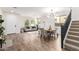 Open-concept living and dining area featuring wood-look tile, white walls, and a modern light fixture at 3875 E Claxton Ave, Gilbert, AZ 85297