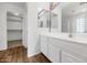 Bathroom featuring a white vanity, and mirrors, and walk-in closet beyond the door at 5787 W Barbara Ave, Glendale, AZ 85302