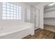 Bathroom with soaking tub, glass block window, shower, and access to walk-in closet at 5787 W Barbara Ave, Glendale, AZ 85302