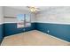 Bedroom with blue accent wall, neutral carpet, ceiling fan, and a window overlooking the neighborhood at 5787 W Barbara Ave, Glendale, AZ 85302