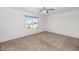 An empty bedroom featuring neutral carpet, white walls, ceiling fan, and a window allowing natural light at 5787 W Barbara Ave, Glendale, AZ 85302