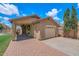Exterior view of the home showcasing a two-car garage, brick driveway, and covered outdoor space at 5787 W Barbara Ave, Glendale, AZ 85302
