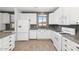 Bright kitchen features white appliances, cabinets, granite countertops, and wood-look tile flooring at 5787 W Barbara Ave, Glendale, AZ 85302