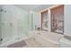 Bathroom featuring a glass-enclosed shower and tub, offers a spa-like experience with natural light, creating a peaceful oasis at 6928 W Oraibi Dr, Glendale, AZ 85308