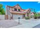 Two-story tan house with a brown roof, two-car garage, desert landscaping, and blue skies at 6928 W Oraibi Dr, Glendale, AZ 85308