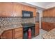Well-equipped kitchen features mosaic backsplash, granite countertops and black oven at 6928 W Oraibi Dr, Glendale, AZ 85308