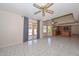 Open-concept living room with ceiling fan, tile flooring, and sliding glass doors to the outside at 6928 W Oraibi Dr, Glendale, AZ 85308