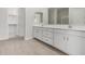 Bathroom vanity with double sinks, white cabinets, and neutral flooring at 6952 E Brushy Bill Rd, San Tan Valley, AZ 85143