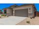 Attractive desert-landscaped front yard with a long driveway and a gray two-car garage at 6952 E Brushy Bill Rd, San Tan Valley, AZ 85143