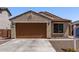Charming single-story home with a brown garage door, desert landscaping, and a tile roof at 7086 W Spur Dr, Peoria, AZ 85383