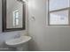 Bright powder room with a pedestal sink, framed mirror, and natural light from the window at 8518 S 8Th Ln, Phoenix, AZ 85041