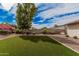 View of a backyard, complete with an artificial grass lawn, mature landscaping, and rock accents at 9265 E Kalil Dr, Scottsdale, AZ 85260
