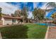 Backyard with a spacious artificial turf lawn, lush landscaping, and a fenced pool area at 9265 E Kalil Dr, Scottsdale, AZ 85260