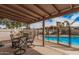 Covered patio features a dining set with views of the fenced pool and lush landscaping at 9265 E Kalil Dr, Scottsdale, AZ 85260