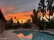 Gorgeous sunset reflects beautifully in the backyard pool surrounded by lush landscaping at 9476 E Laurel Ln, Scottsdale, AZ 85260