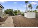 Serene backyard featuring gravel ground cover, mature trees, and a white storage shed at 15064 N 54Th Way, Scottsdale, AZ 85254