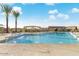 Large community pool featuring fountains, umbrellas, lounge chairs, and manicured palm trees at 20747 E Arroyo Verde Dr, Queen Creek, AZ 85142