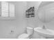 Powder room featuring a toilet, sink, round mirror, and window with shutters at 29475 N Candlewood Dr, San Tan Valley, AZ 85143
