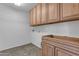 The laundry room features tile floors and wood cabinets and an electrical hookup at 29475 N Candlewood Dr, San Tan Valley, AZ 85143