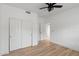 Spacious bedroom featuring wood-look floors, white walls, ceiling fan, closet, and access to another room at 3102 E Desert Broom Way, Phoenix, AZ 85048