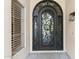 Elegant arched front door with decorative ironwork and a sidelight window at 3102 E Desert Broom Way, Phoenix, AZ 85048