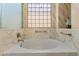 Stylish bathroom showcasing soaking tub with marbled accents, decorative window, and neutral tones at 3225 E Cardinal Ct, Chandler, AZ 85286