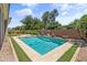 Beautiful backyard pool featuring mature landscaping, artificial turf and a brick privacy wall, perfect for relaxation at 3225 E Cardinal Ct, Chandler, AZ 85286