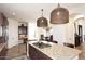 Open-concept kitchen featuring a granite island, custom lighting, and seamlessly connected dining area at 36674 N Vasari Dr, Scottsdale, AZ 85262